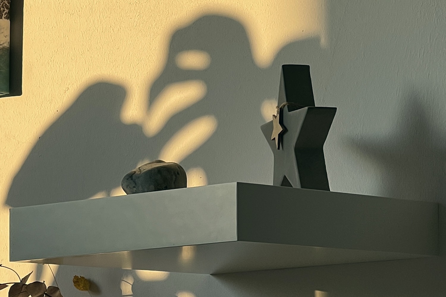 Regal mit Stern und Stein, dahinter ein weiches Schattenspiel an der Wand im goldenen Abendlicht