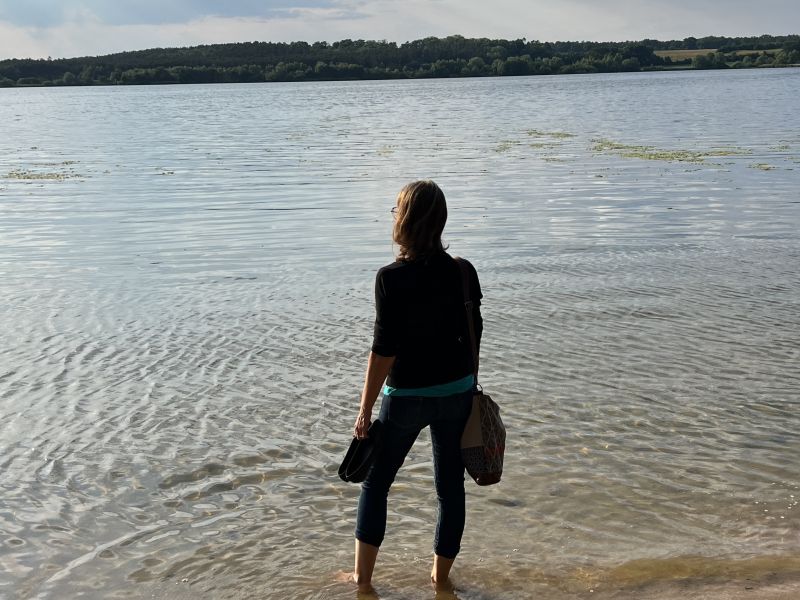 Frau steht allein am See und schaut in die Weite – Stille und Selbstreflexion