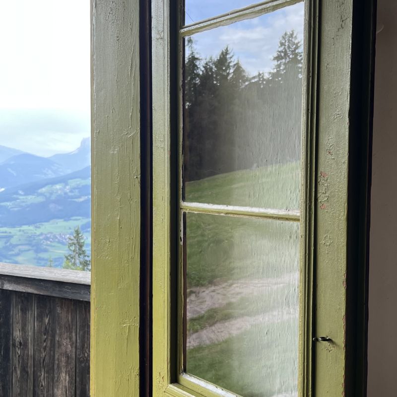 Blick durch ein altes grünes Fenster auf eine weite Berglandschaft – Symbol für neue Perspektiven und innere Veränderung